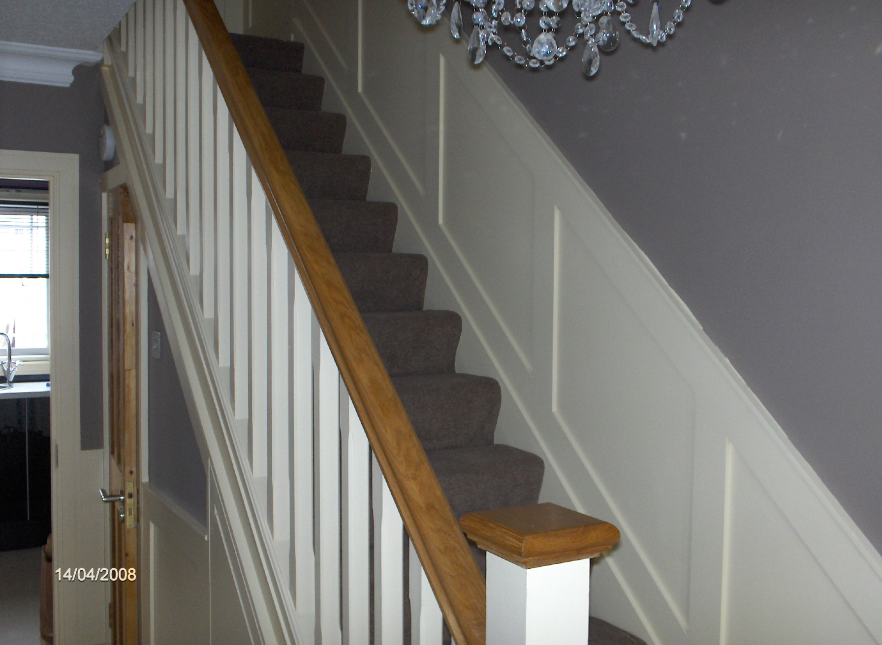 Oak handrail with cream square spindles, and oak caps, with cream wall panelling to match.and understairs toilet constructed. with solid oak doors,
