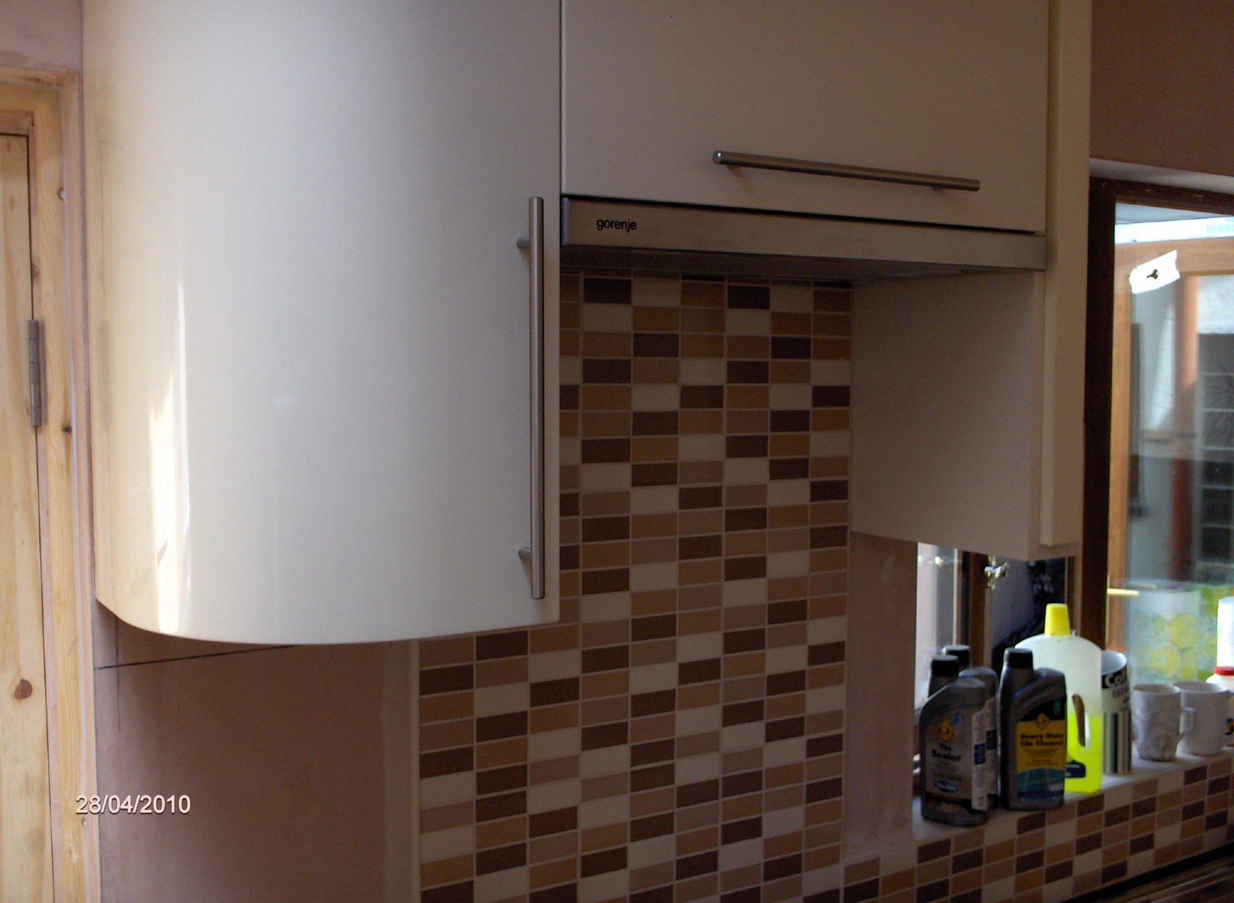fitted kitchen, with curved wall unit and door. and slimline telescopic extractor, naxos cream high gloss doors



